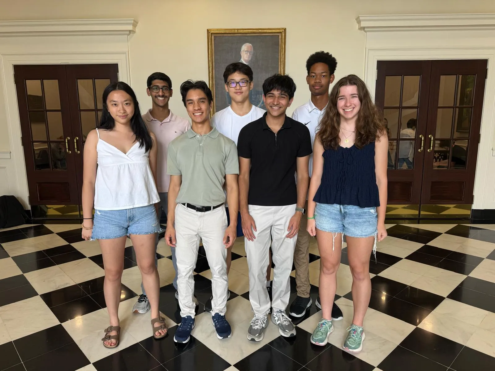 Seven members of the Rule the Board team standing together on a black and white checkered floor.